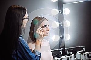 Pretty attractive makeup artist combing the eyebrows