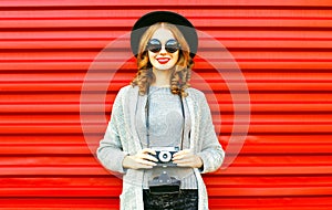 Pretty autumn happy girl holds retro camera on red background photo