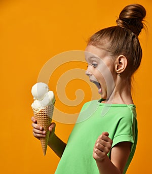 Pretty baby girl kid eating licking banana and vanilla ice cream in waffles cone