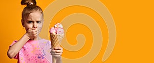 Pretty baby girl kid hold strawberry ice cream in waffles cone on yellow background banner