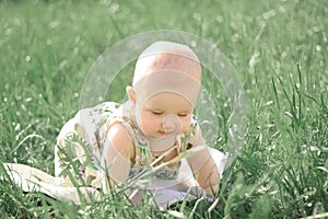 Pretty baby girl on the lawn in the spring day