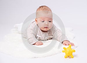 Pretty baby plays on the floor with a toy