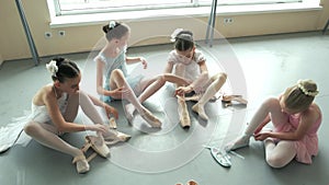 Pretty ballet dancers putting on pointe shoes.