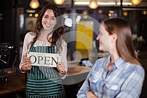 Pretty barista holding open sign