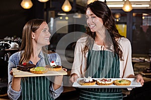 Pretty baristas holding desserts