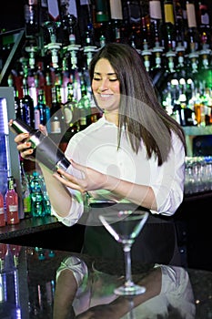 Pretty bartender mixing a cocktail drink in cocktail shaker