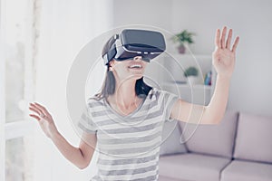 Pretty beautiful cute excited woman in VR headset looking up and trying to touch objects in virtual reality