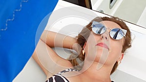 Pretty beautiful girl with light brown hair lies on yacht and sunbathing