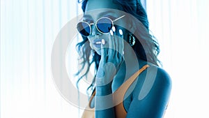 Pretty beautiful sensual young hipster woman in sunglasses in a stylish swimsuit with trendy manicure enjoys ultraviolet rays in a