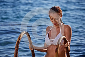 Pretty beautiful woman in white swimwear bikini posing in blue sea water