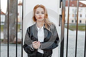 Pretty beautiful young blond woman in a black spring stylish jacket in black jeans in white shirt stands