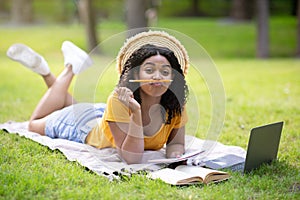 Pretty black girl being silly and making faces during studies with laptop at park