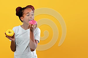 Pretty black girl holding delicious colorful donuts