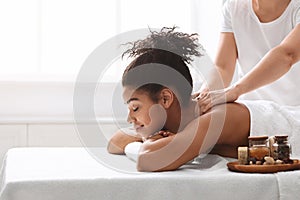 Pretty black woman enjoying body massage with aromatherapy