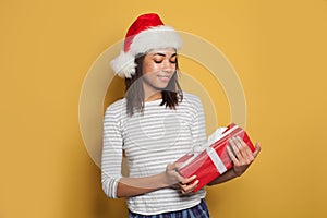 Pretty black woman Santa with red Christmas gift on vibrant yellow banner background