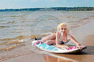 Pretty blond girl model like Marilyn Monroe with surfing board on a beach