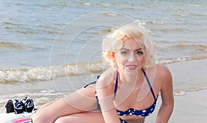 Pretty blond girl model like Marilyn Monroe with surfing board on a beach