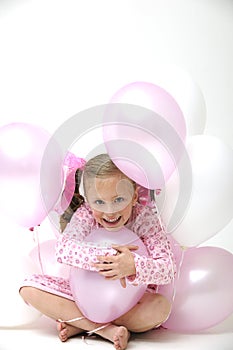 Pretty blond girl sitting between pink balloons