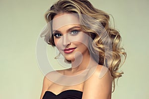 Pretty blond-haired model with curly, loose hairstyle and attractive makeup.