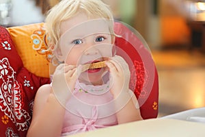 Pretty blond little girl eats bread