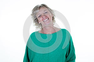 Pretty blond senior happy woman smiling in green top sweater on white background