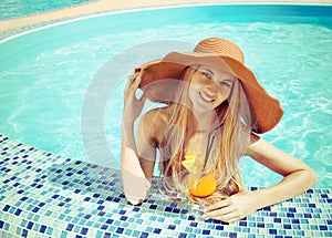 Pretty blond woman in a hat enjoying cocktail