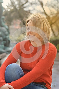 Pretty blond woman sitting in a park with backlight