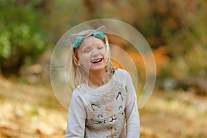 Pretty blond young girl laughing outdoors on a beautiful sunny autumn day.