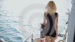 Pretty blonde in the black short dress resting on board of the ship