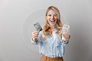 Pretty blonde business woman posing isolated grey wall background holding two credit cards