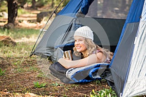 Pretty blonde camper smiling and lying in tent