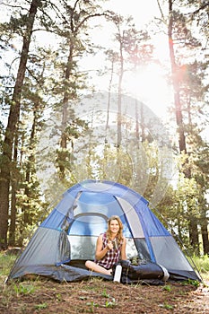 Pretty blonde camper smiling and sitting in tent