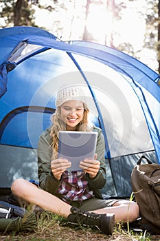 Pretty blonde camper using tablet and sitting in tent