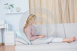 Pretty blonde on couch typing on laptop