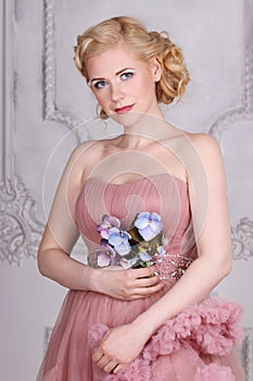 Pretty blonde in dress with hairdo with flowers poses