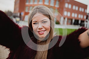 Pretty blonde girl in the park making herself a photo