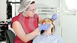 Pretty blonde girl in protective yellow glasses on the stamotologist examined her open mouth. Female dentist examines