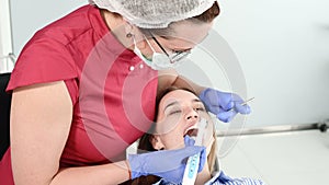 Pretty blonde girl in protective yellow glasses on the stamotologist examined her open mouth. Female dentist examines