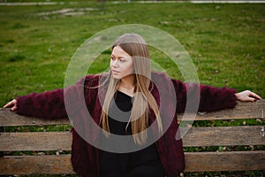 Pretty blonde girl sittig in a bench in the park