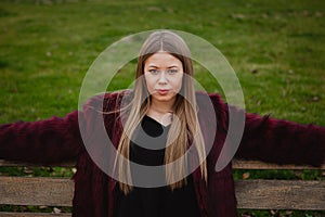 Pretty blonde girl sittig in a bench in the park