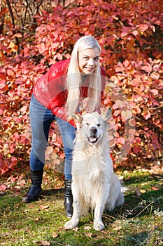 Pretty blonde girl walking with dog in the forest. Animal concept.