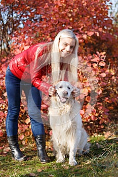 Pretty blonde girl walking with dog in the forest. Animal concept.