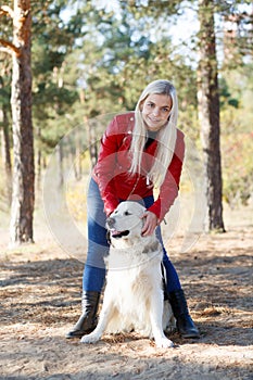 Pretty blonde girl walking with dog in the forest. Animal concept.