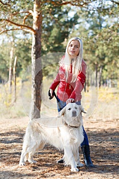 Pretty blonde girl walking with dog in the forest. Animal concept.