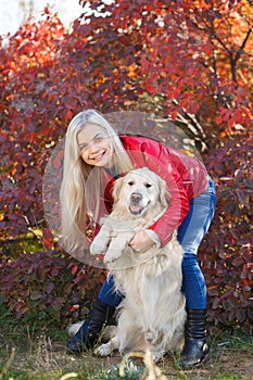 Pretty blonde girl walking with dog in the forest. Animal concept.