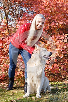 Pretty blonde girl walking with dog in the forest. Animal concept.