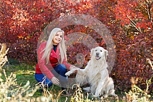 Pretty blonde girl walking with dog in the forest. Animal concept.