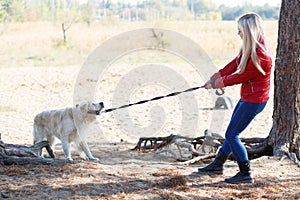 Pretty blonde girl walking with dog in the forest. Animal concept.