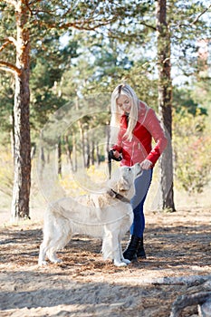 Pretty blonde girl walking with dog in the forest. Animal concept.