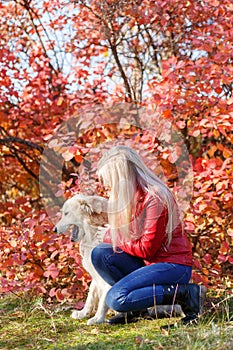 Pretty blonde girl walking with dog in the forest. Animal concept.